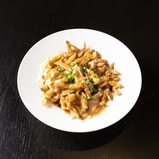 Plate of poutine with fries, cheese curds, gravy, and green onions.