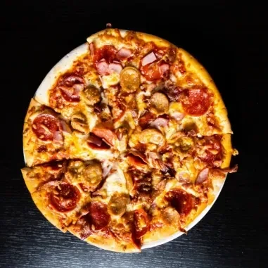Round pizza with meat toppings on a plate, one slice missing.