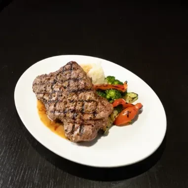 Well-plated grilled steak with grill marks, potatoes, and vegetables.