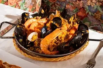 Close-up of vibrant seafood paella with mussels and shrimp in a metal pan.