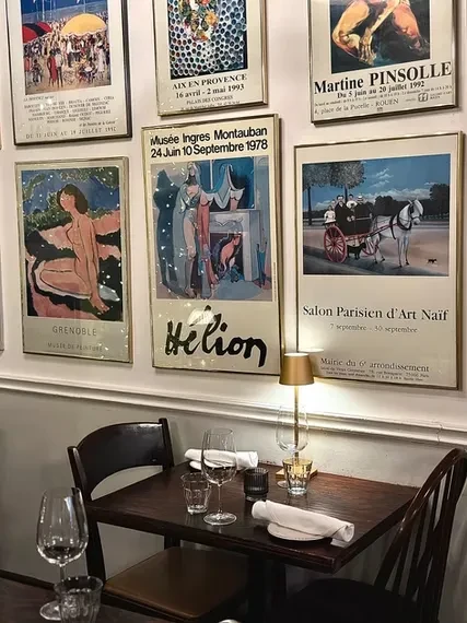 Cozy restaurant interior with a table set for two and French art posters.