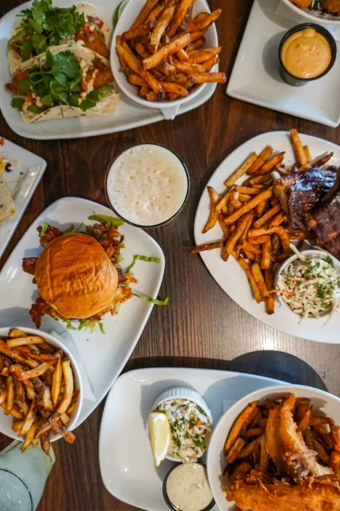 Overhead view of tacos, burger, ribs, fish, fries, and a beer.