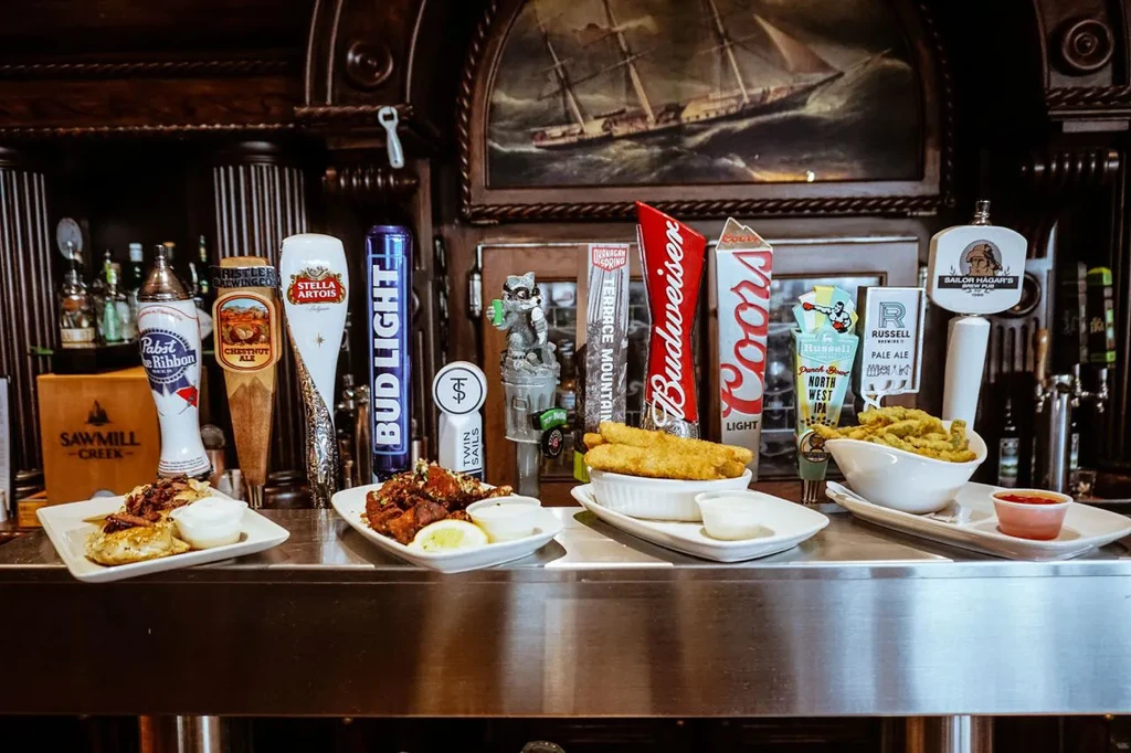 Fried food plates and many beer taps at a bar.