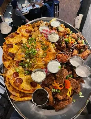Large platter of nachos, pepperoni flatbreads, fried bites, and various dips.