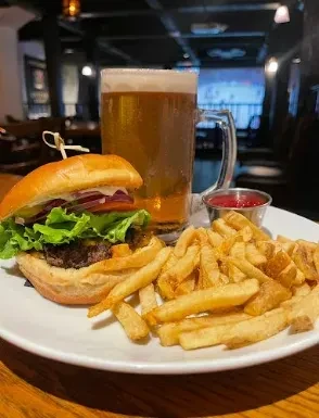 Close-up of a hamburger, fries, ketchup, and beer in a restaurant.