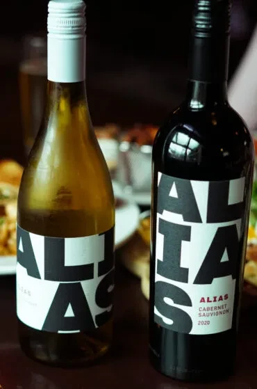 Two Alias white and red wine bottles in a restaurant setting.