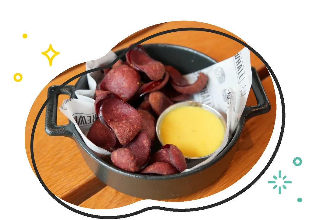 Deep red chips and yellow dip in a cast-iron skillet on wood.