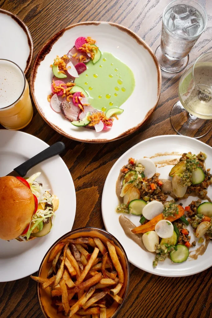 Overhead shot: dark wooden table laden with diverse dishes and drinks.