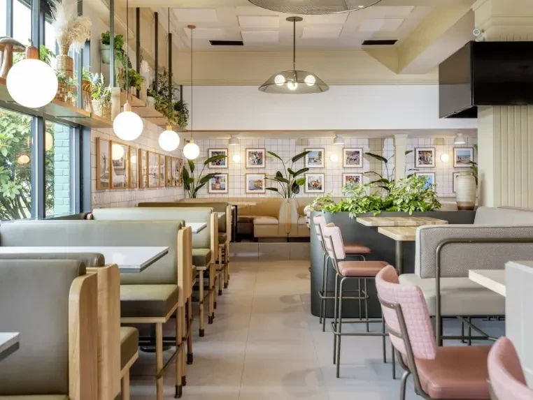 Empty modern restaurant interior with green booths and pink bar stools.
