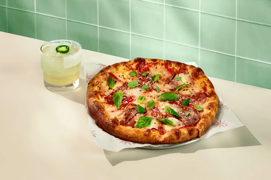 Freshly baked pizza with basil, pepperoni, and an iced jalapeño cocktail.