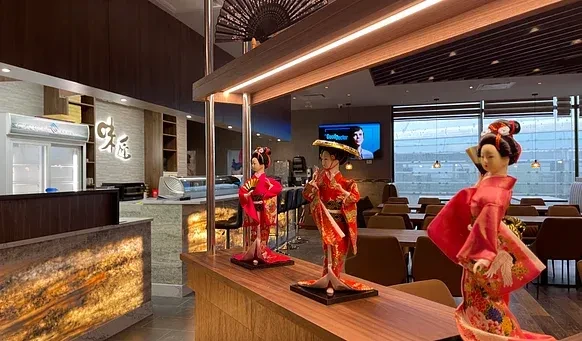Three ornate Japanese geisha dolls displayed in a modern restaurant.