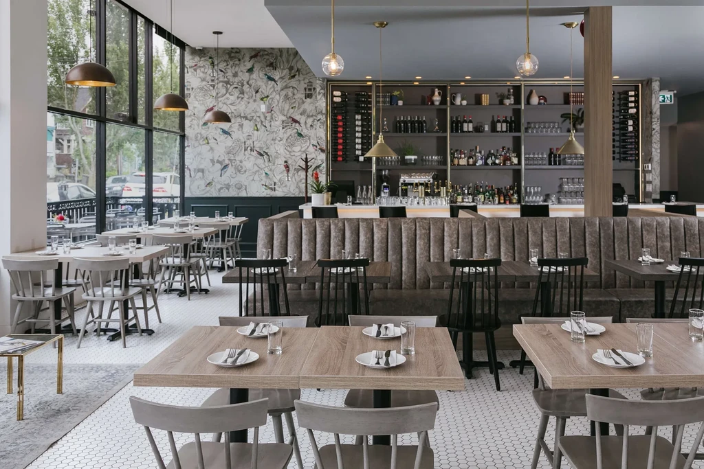 Modern, empty restaurant interior featuring dining area, bar, and bird wallpaper.