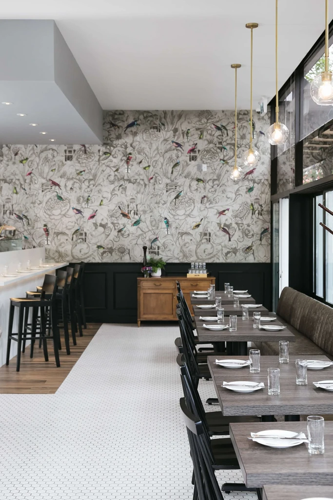 Empty modern restaurant interior with botanical bird wallpaper.