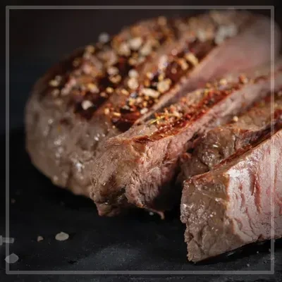 Seasoned, grilled steak with visible grill marks, sliced medium-rare.