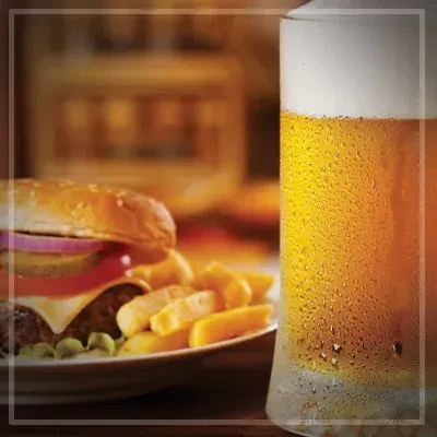 Close-up of a cheeseburger, golden fries, and frosty beer.