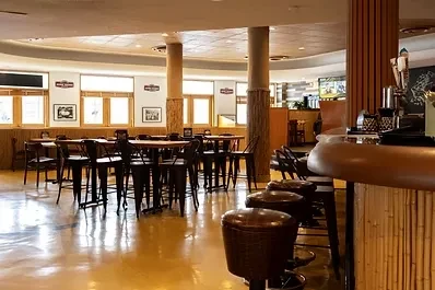 Empty restaurant dining room and bar with tables, chairs, and bamboo accents.