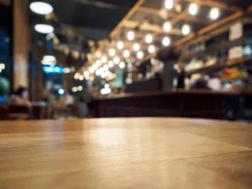 Warm, blurred bar interior with glowing spherical lights and a wooden table.