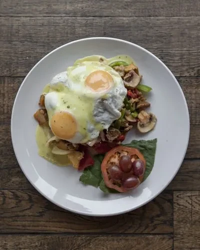 Top-down eggs with green sauce, hash, and side tomato.