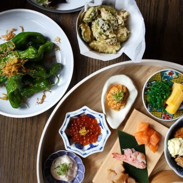 Overhead view of diverse Japanese dishes artfully arranged on a wooden tray.