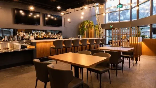 Modern restaurant interior with a well-stocked bar and dining tables.