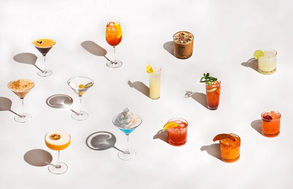 Twelve distinct cocktails and beverages artfully arranged on a white background.