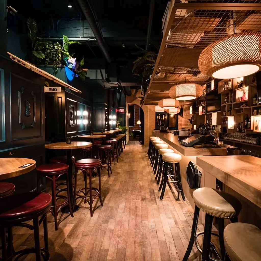 Elegant bar with long counter, tables, woven lights, and animal head.