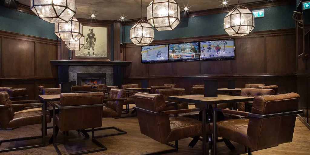 Sophisticated restaurant interior with fireplace, sports TVs, and tufted leather seating.