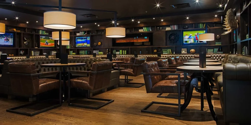 Upscale library-themed bar with dark wood, leather, and background sports TVs.
