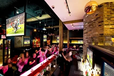 Patrons cheer enthusiastically at a lively sports bar watching football.
