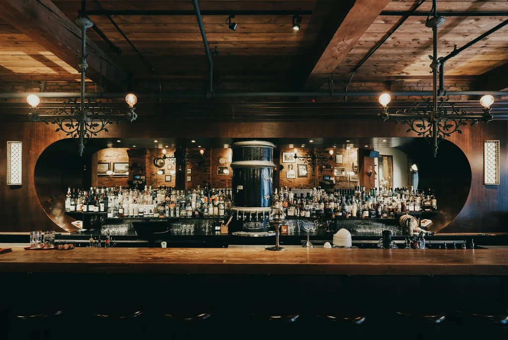 Dimly lit bar interior featuring a well-stocked wooden back bar.