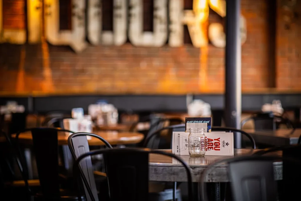 Industrial restaurant table with a mason jar and "YOU ARE LOCAL" card.