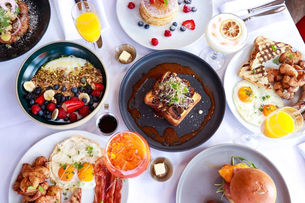 Vibrant overhead view of a diverse brunch spread on a white tablecloth.