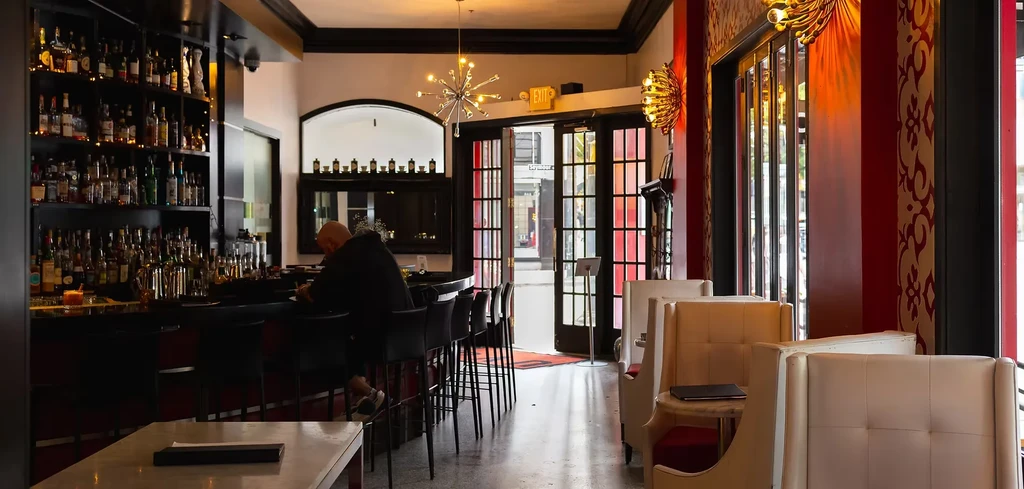 Elegant bar and restaurant interior with person at bar and booths.