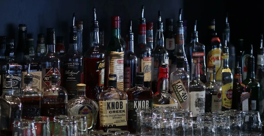 Well-stocked bar with rows of liquor bottles and stacked glasses.