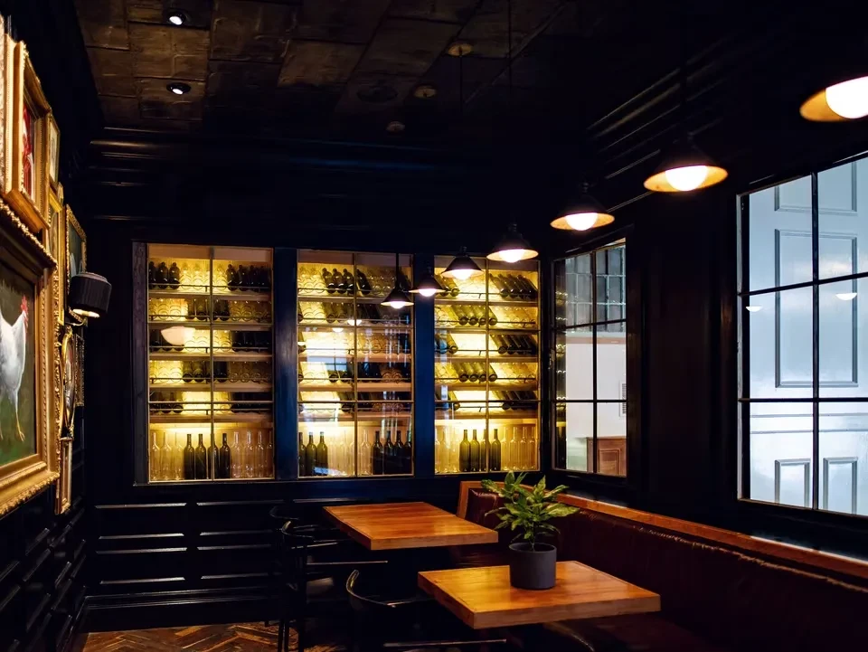 Dark, upscale restaurant interior with a large, backlit wine display and seating.