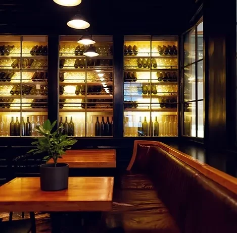 Illuminated wine wall in a dark, elegant restaurant with seating.