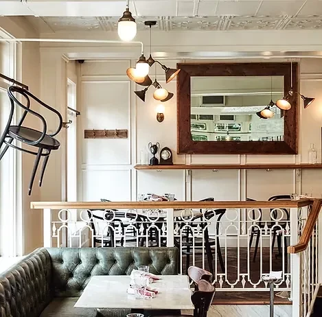 Multi-level restaurant with green booth, marble table, and ornate ceiling.