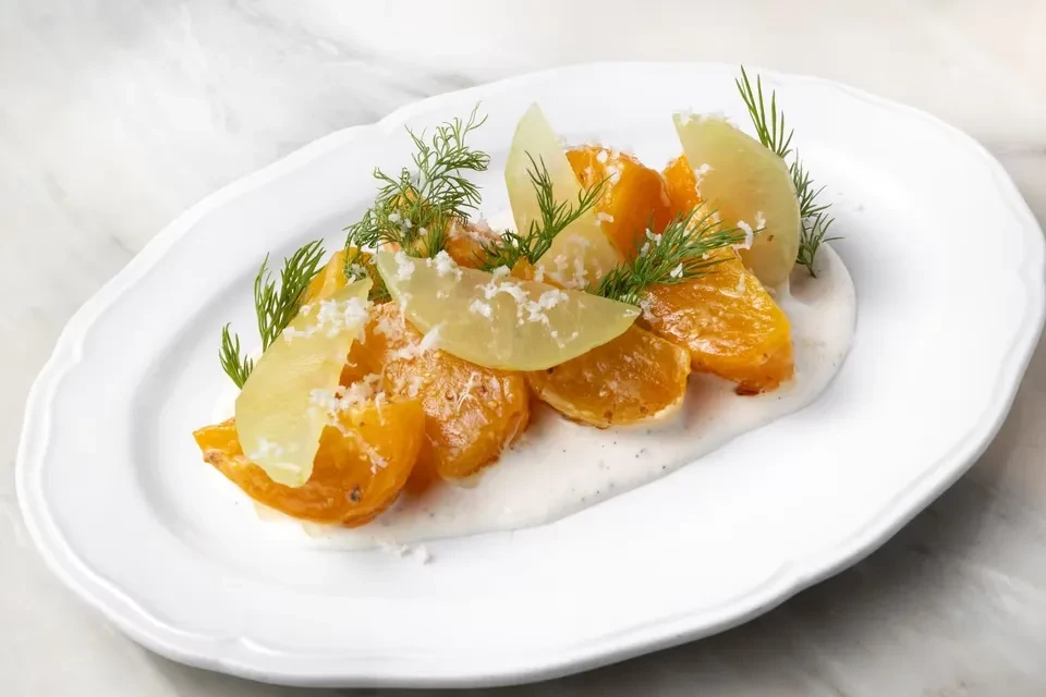 Artfully plated roasted golden slices with creamy sauce and garnishes.