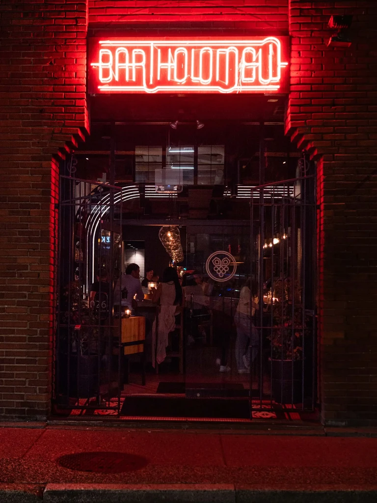 Bar Holongo exterior at night, red neon sign, patrons visible inside.