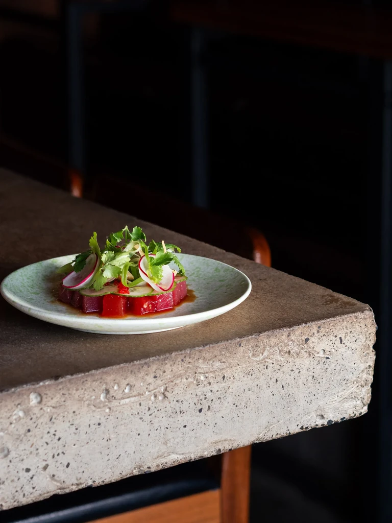 Red tuna tartare with cilantro, cucumber, and radish on green plate.