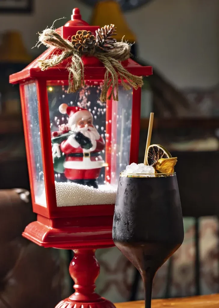 Red Santa lantern and dark, frosted cocktail with dried citrus.