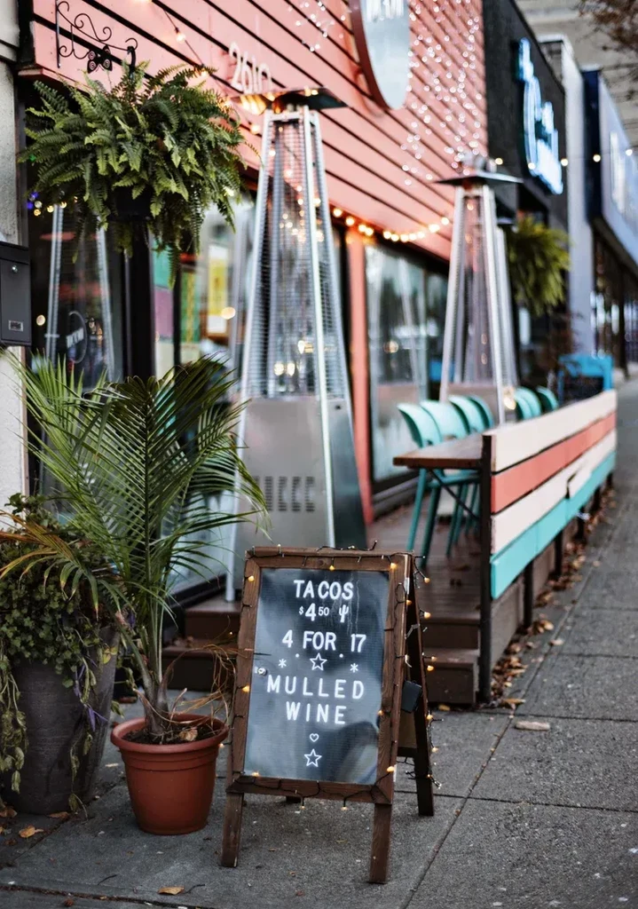 Peach restaurant exterior with string lights, outdoor dining, and taco sign.