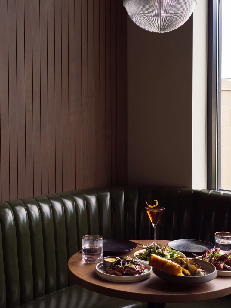 Elegant restaurant interior, round wooden table with small plates and drinks.