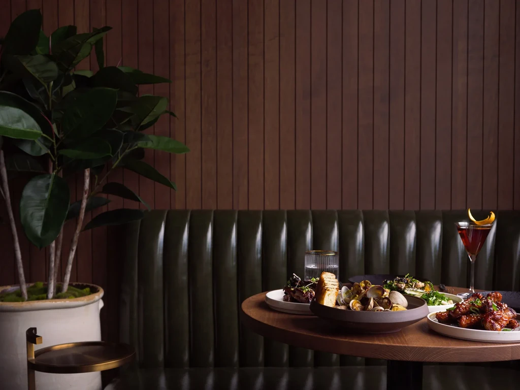 Elegant restaurant table with clams, chicken wings, martini, and water.