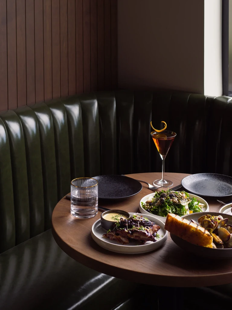 Restaurant booth table with a martini, salad, main course, and seafood.