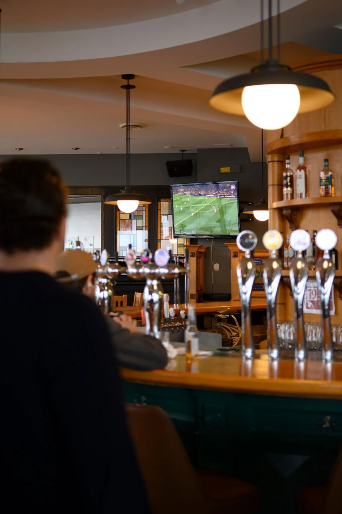 Bar interior, beer taps, and a soccer match on TV.