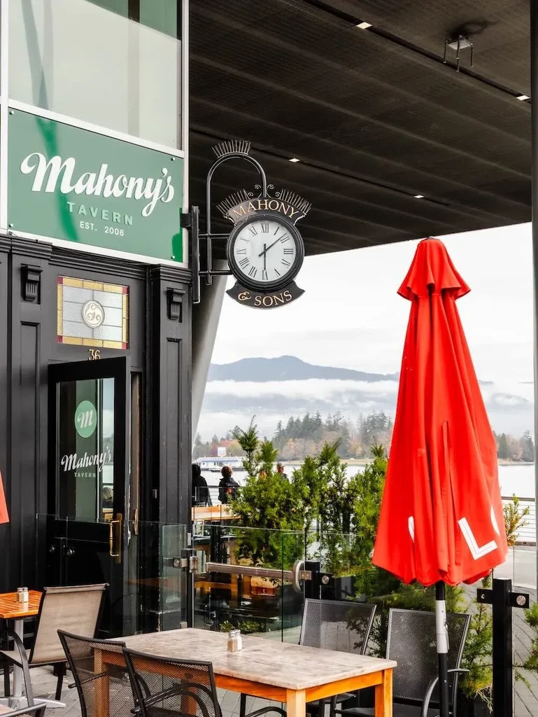 Mahony's Tavern exterior with patio overlooking lake, autumnal trees, misty mountains.