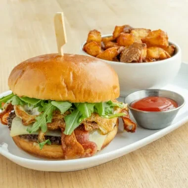 Gourmet burger with roasted potatoes and ketchup on a plate.