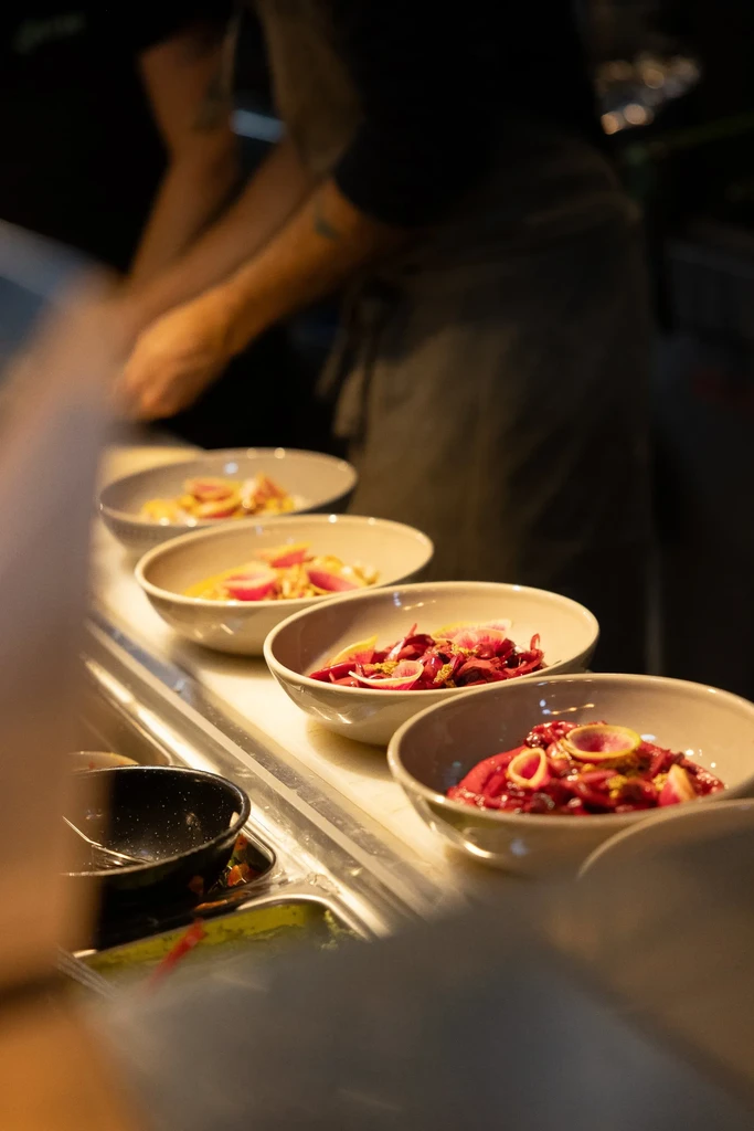 Five bowls of vibrant food on a counter, chef plating.