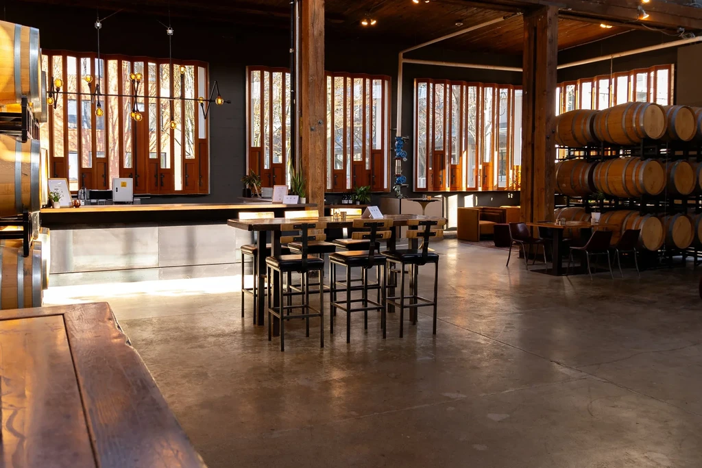 Spacious, modern winery tasting room with wine barrels and industrial-chic decor.